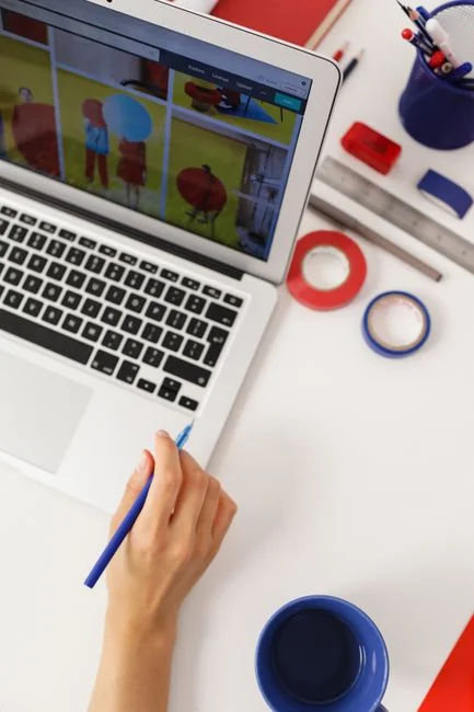 An adult uses a credit card for online shopping on a laptop indoors.
